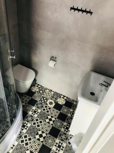 ein Badezimmer mit einem weißen WC und einem schwarz-weißen Fliesenboden in der Unterkunft Chyża Zagroda in Jaworki