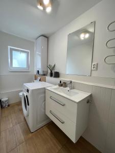 a white bathroom with a washing machine and a mirror at Amira Apartman in Komárno