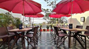 a row of tables and chairs with red umbrellas at STAYMAKER Hotel Mohan Palace in Baharampur