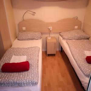 a room with two beds and a table with a red pillow at Camping Park Soline - Rose PB -Mobile Home in Biograd na Moru
