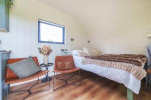 a bedroom with a bed and two chairs and a window at Luna's Lookout in Cilcain