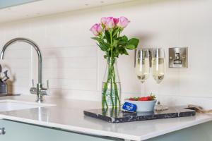 un vase de fleurs roses sur un comptoir avec des verres à vin dans l'établissement Luna's Lookout, à Cilcain