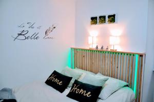 Schlafzimmer mit einem Bett mit einem Kopfteil aus Holz und Kissen in der Unterkunft Dormir à Brioude - appartement 'esprit zen' in Brioude