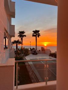 een balkon met palmbomen en uitzicht op de zonsondergang bij White SideSea View Apartment in Sarandë