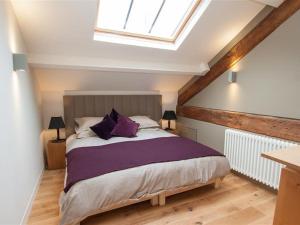 a bedroom with a large bed with purple pillows at Sunny Brow Hayloft in Ambleside