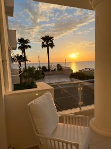 een witte stoel op een balkon met een zonsondergang bij White SideSea View Apartment in Sarandë
