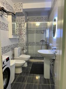 een badkamer met 2 toiletten, een wastafel en een douche bij White SideSea View Apartment in Sarandë