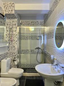 een badkamer met een douche, een toilet en een wastafel bij White SideSea View Apartment in Sarandë