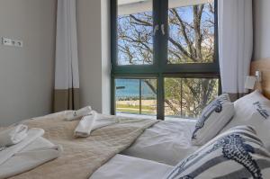 ein großes Bett in einem Zimmer mit einem großen Fenster in der Unterkunft Apartament z widokiem na morze - Nadmorski Luksus Apartamenty in Ustronie Morskie