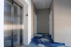 an empty hallway with doors and blue carpet at Apartament z widokiem na morze - Nadmorski Luksus Apartamenty in Ustronie Morskie