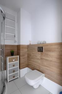 ein Badezimmer mit einer weißen Toilette und einer Holzwand in der Unterkunft Apartament z widokiem na morze - Nadmorski Luksus Apartamenty in Ustronie Morskie + 20 Fotos