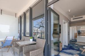 a balcony with a table and chairs and glass doors at Apartament z widokiem na morze - Nadmorski Luksus Apartamenty in Ustronie Morskie