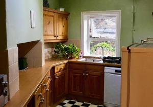 kuchnia z drewnianymi szafkami, umywalką i oknem w obiekcie Green Gable w mieście Skipton