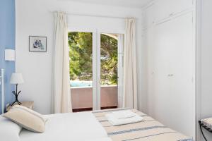 een witte slaapkamer met een bed en een raam bij Villa Ponte - Cala Galdana in Cala Galdana