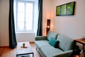 ein Wohnzimmer mit einem grünen Sofa und einem Tisch in der Unterkunft Dormir à Brioude - appartement 'esprit zen' in Brioude