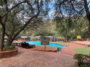 a swimming pool with a sign in a park at Pumula Bush Chalet in Mabula