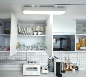eine Küche mit weißen Schränken und einer Mikrowelle in der Unterkunft Angel House in Daegu