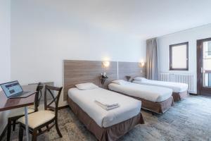 a hotel room with three beds and a desk at Hôtel du Helder in Lyon