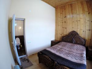 a small bedroom with a bed and a mirror at Guesthouse Lenjeri in Mestia