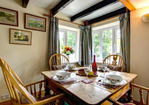 a dining room with a wooden table and chairs at Foss Garth Cottage in Thwaite