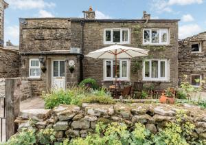 a stone house with an umbrella in front of it at Foss Garth Cottage in Thwaite