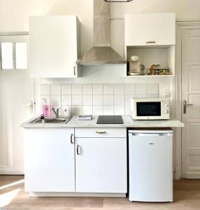 a white kitchen with white cabinets and a microwave at Élégant studio rénové in Boulogne-sur-Mer +7 photos