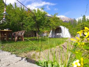 a tent and a table and chairs in a field at Grapes Garden Resort Hunza in Hunza