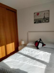 Un dormitorio con una cama blanca con un corazón en la pared en PISO COLLAZO, en A Illa de Arousa