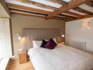 um quarto com uma grande cama branca com almofadas roxas em Bracken Barn em Ambleside