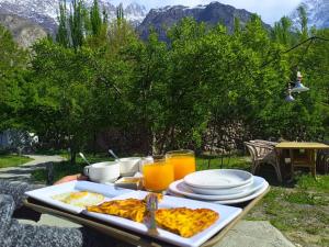 a table with a tray of food and orange juice at Grapes Garden Resort Hunza in Hunza