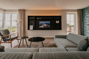 a living room with a couch and a tv at Residence Oude Haven Colijnsplaat appartementen met verdieping in Colijnsplaat