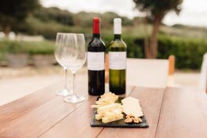 dos botellas de vino y dos copas en una mesa de madera en Hotel Rural Sant Patrici, en Ferreries