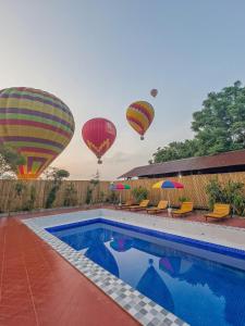 a group of hot air balloons flying over a swimming pool at Vang Vieng Chill House in Vang Vieng