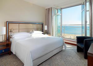 a bedroom with a large white bed and a large window at Sheraton Sopot Hotel in Sopot