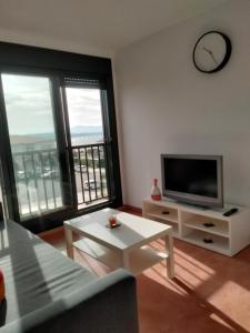 a living room with a television and large windows at PISO COLLAZO in Isla de Arosa