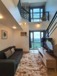 ein Wohnzimmer mit einem Sofa und einem Flachbild-TV in der Unterkunft BGC Loft in Avant, stunning golf view! in Manila