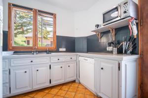 una cocina con armarios blancos y una ventana en Le Petit Lieu Les Orres Appartement Charmant, en Les Orres