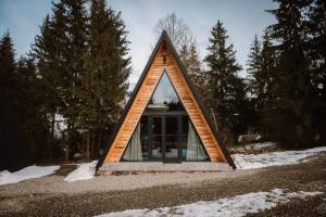 a small house with a triangular roof in a forest at Cazare Nemes Szállás in Joseni