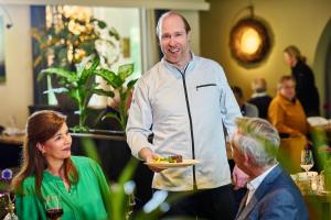 a man holding a plate of food with a woman at Hotel 't Kruisselt in De Lutte