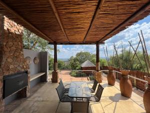 a patio with a table and chairs under a wooden roof at Pumula Bush Chalet in Mabula