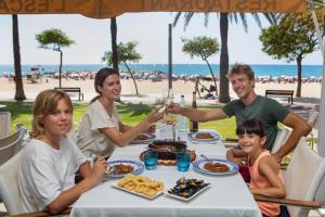 ミアミ・プラトーヤにあるCasa Carmen 2の海辺の食卓に座って食事をする家族