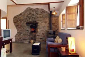 sala de estar con chimenea de piedra, sofá y TV en Apartamentos Hacienda Llamabua, en Navia