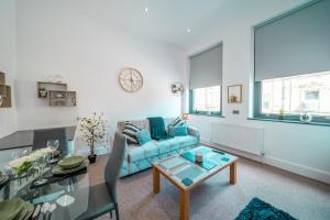 a living room with a blue couch and a glass table at Cozy 1-Bedroom Apartment in the Heart of Barnsley Town Centre in Barnsley