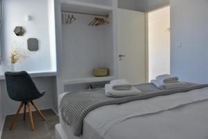 a white bedroom with a bed and a chair at Relaxia Estate Naxos in Galini