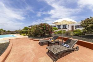 Las BreñasにあるJaretas - Apartamento rural con piscinaのパティオ(椅子2脚、パラソル付きテーブル付)