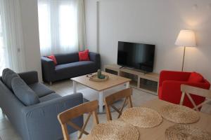 een woonkamer met banken en een tafel en een televisie bij Kaya Suite Sunrise in Fethiye