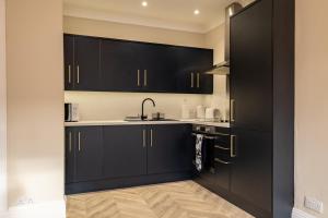 una cocina con armarios negros y fregadero en Modern City Stay - SJA Stays - 2 Bed Apartment, en Aberdeen