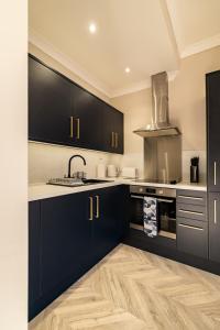 una cocina con armarios negros y fregadero en Modern City Stay - SJA Stays - 2 Bed Apartment, en Aberdeen