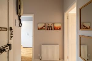 a hallway with two pictures on the wall and a radiator at Modern City Stay - SJA Stays - 2 Bed Apartment in Aberdeen