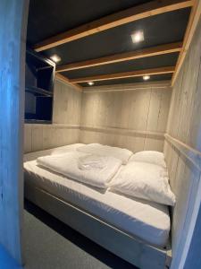 Bett in einem kleinen Zimmer mit weißer Bettwäsche in der Unterkunft Safari Lodge, glamping aan zee! in Callantsoog
